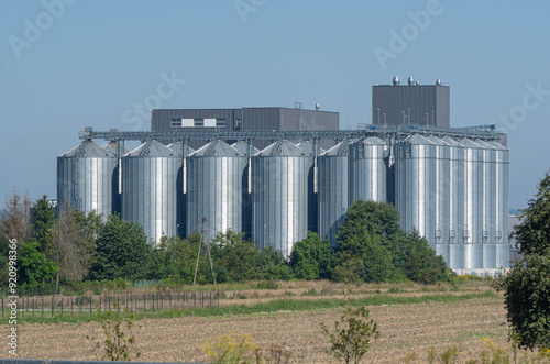  zakład przetwórczy z dużymi zbiornikami typu silos na tle otaczających łąk i zieleni