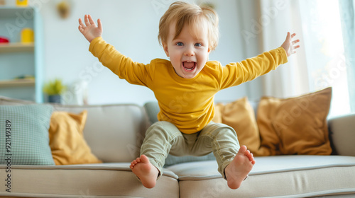 Joyful naughty child boy jumping and having fun on sofa