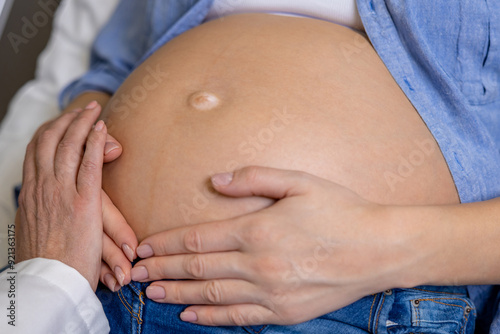 Close up of a pregnant woman on third trimester with hands on her belly