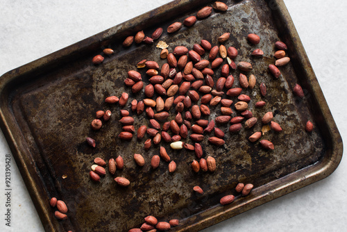 Overhead view of unpeeled raw peanuts on a baking tray, flatlay of raw peanuts on a roasting tray, process of making roasted peanuts