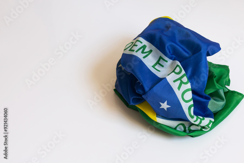 Poorly folded Brazilian flag on a white background with part of the phrase Ordem e Progresso appearing