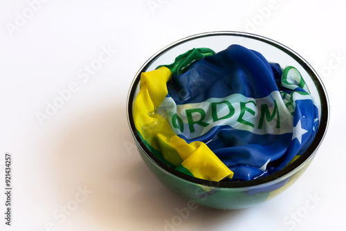 Brazilian flag soaking in water inside a glass container with the word order on top