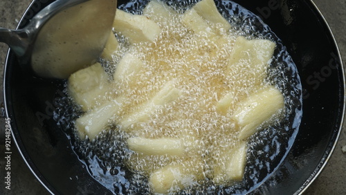 Cassava is being fried on a frying pan. Fried cassava is a traditional Indonesian food. Focus selected