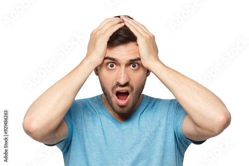 Shock content. Surprised young man in blue t-shirt shouting, holding his head with both hands