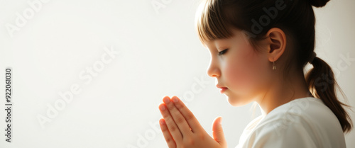 Young girl praying with hands clasped together