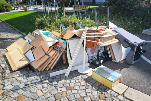 A heap of assorted discarded household items and furniture piled up on a cobblestone street, depicting a bulk waste collection day in an urban environment.