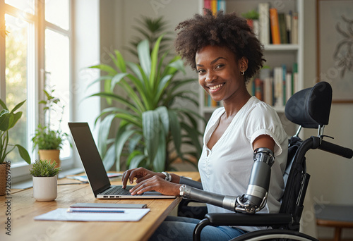 A woman in a wheelchair with prosthetic arms works on a laptop computer at a table