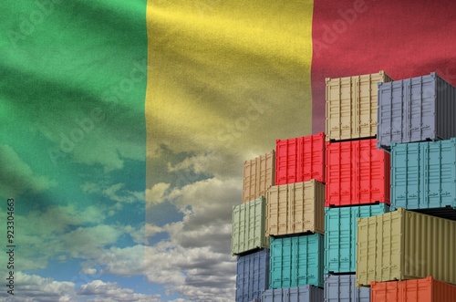 Mali flag and big stack of shipping cargo containers in docks with sky background close up