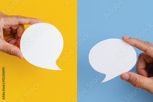 Conceptual image about communication and social media, customer feedback, hand hold blank couple real white speech bubble paper cut on yellow and blue color background