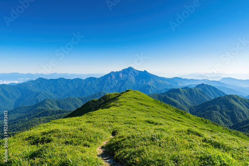 A picturesque view of a lush green mountain range under a clear blue sky, perfect for nature lovers and outdoor enthusiasts capturing serene landscapes.