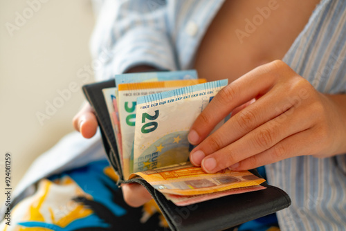 Teen holding wallet with Euro bills, symbolizing pocket money, savings or planning for future dreams, currency handling, monetary value