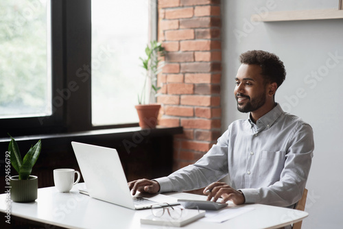 Young man student using laptop computer at home, studying online. Creative professional working in office. Distance study, work from home, e-learning, business, meeting online