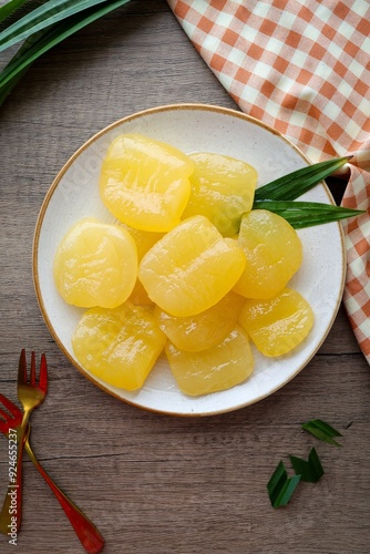 Toddy palm in syrup in a white ceramic with golden fork plate on wooden background , thai dessert , thai called luk tan chuem