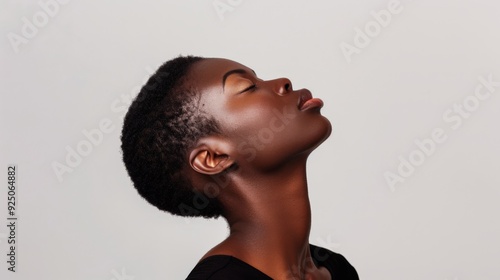 Elegant African American woman in a minimalist studio, wearing a black top, head tilted back with eyes closed, pure white backdrop, poised demeanor, showcasing natural beaut confidence.