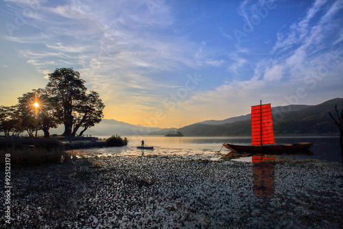 Yangpyeong-gun, Gyeonggi-do, South Korea - July 11, 2015: Sunrise view of a boatman on ferry with Hwangpo Sailboat on Namhan River at Dumulmeori in summer