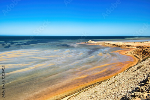 Sandbars, rusty-red ferrous sand and low limestone cliffs at the shallow coast of Eagle Bluff, Shark Bay, Denham, Western Australia. 