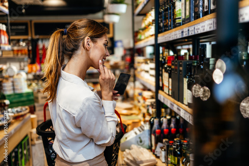 Beautiful young and elegant woman buying some healthy food and drink in modern supermarket or grocery store. Lifestyle and consumerism concept.