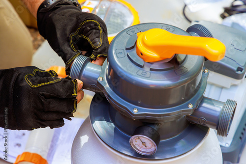 Pool maintenance worker assembles sand filter system tank equipment for cleaning swimming pool