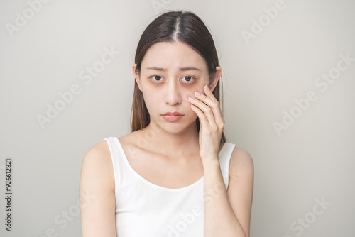 Bored, insomnia asian young woman, girl looking at camera, hand touching under eyes with problem of black circles or panda puffy, swollen and wrinkle on face. Sleepless, sleepy healthcare person.