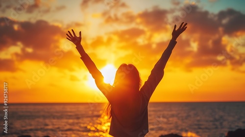 woman cheering at sunrise by the beach with outstretched arms