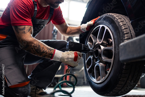 Tire shop mechanic using pneumatic screw gun to remove the wheel. Replacing tires on the car.