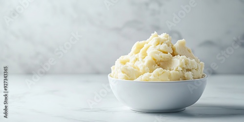 A clean white marble background contrasts with a white bowl of bright and buttery, lumpy mashed potatoes with a big space on it for textual or background use, Generative AI.