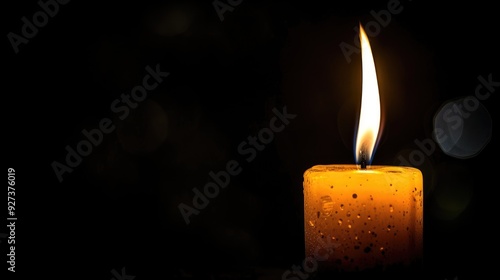 Candle aflame against dark backdrop