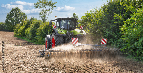 Tractor with cultivator working at the edge of the field after the grain harvest - No.2045