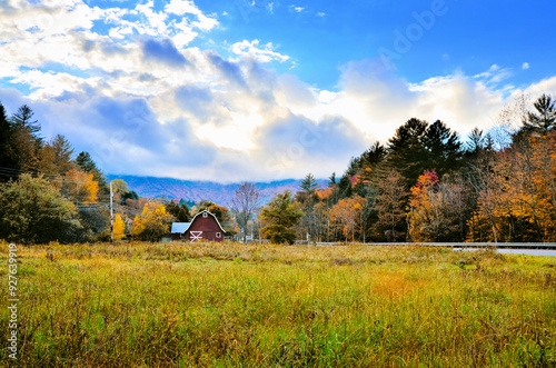 Rustic old red barn during autumn with colorful fall leaves and dramatic skies, Vermont, USA