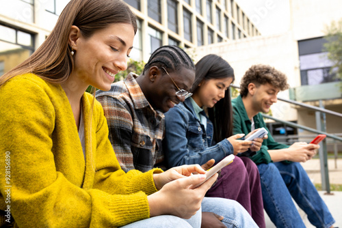 Group of happy multiracial teenage college friend students ignoring each other looking at mobile phone. Smartphone addiction.