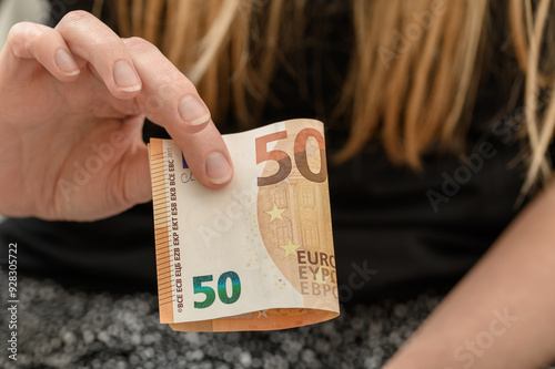 Banknot 50 euro trzymany w ręce przez biedna kobietę 