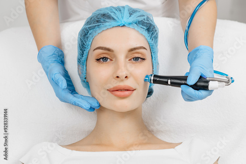 A cosmetologist wearing gloves performs vacuum cleaning and polishing of the facial skin of a middle-aged woman in a cosmetology clinic. Professional moisturizing and rejuvenating hardware procedures.