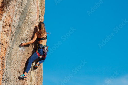 The girl climbs the rock. The climber is training to climb the rock. A strong athlete overcomes a difficult climbing route. Extreme hobby. .