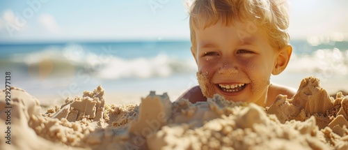  A child closely situated in the sand, grains covering his face, behind lies an expansive beach scene