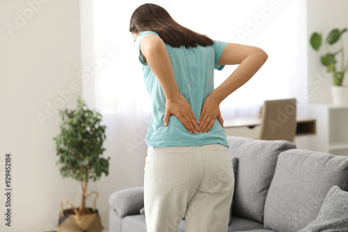 Young woman suffering from back pain at home