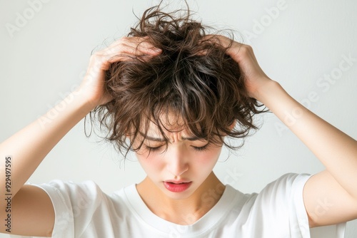 Frustrated with Frizz: A young woman with short, curly hair runs her hands through it in frustration, showcasing the common struggle of unruly hair. The image captures the relatable feeling of battli