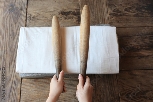 Wolmido Island, Jung-gu, Incheon, South Korea - April 15, 2022: Top angle view of female hands holding two fulling mallets on white cloth and fulling stone at Yangjindang House of Wolmido Park