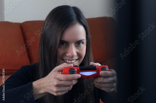 Mujer aficionada jugando videojuegos con euforia y soteniendo el control inalámbrico muy cerca de su cara. 