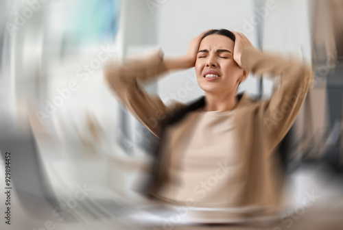 Woman suffering from headache indoors, motion blur effect