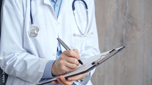 Healthcare professional doctor writing medical records on a clipboard. Female unrecognizable physician at work. Medicine and pharmacy