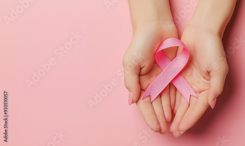 Hands gently holding pink ribbon on pink background, breast cancer awareness support or women's health advocacy concept, compassionate gesture symbolizing hope and solidarity