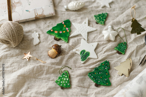 Modern authentic Christmas ornaments. Stylish handmade clay tree,star and mushrooms with scissors and thread on rustic table. Christmas gift decor. Winter handcraft and holiday preparation