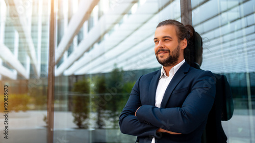 Confidence successful businessman in suit with beard standing in front of office glass building lean on wall arm crossed looking away and smile. Hispanic modern business man portrait. Banner