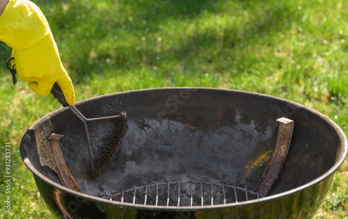 Czyszczenie metalowego paleniska w grillu ogrodowym ze starych osadów powstałych po spalaniu resztek tłuszczu i węgla drzewnego