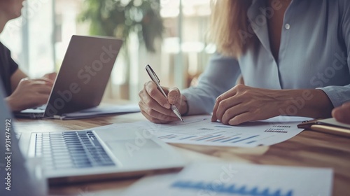 A professional financial advisor sitting at a desk with a laptop, discussing investment options with a client, light solid color background