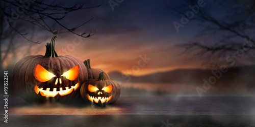 A scary spooky glowing carved halloween pumpkin lantern, Jack O' Lanterns, on the left of a wooden product display bench on a scary halloween night.