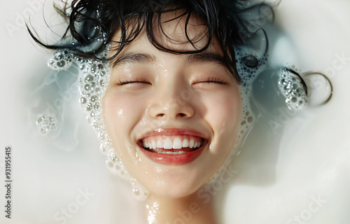 Happy Assian woman with closed eyes smiling while taking bath with milk. Luxury beauty concept