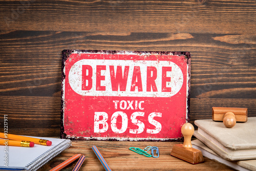 Toxic Boss. Beware sign with text on a wooden texture office table