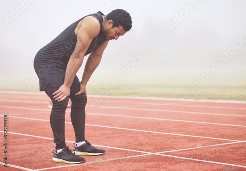 Breathe, fitness and man on track from exercise, marathon training and cardio workout at stadium. Sports, athlete and person for rest, recovery and health for performance, endurance and running