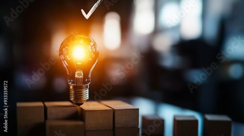 A glowing light bulb set on wooden blocks, with a checkmark overhead, conveying the notion of an innovative idea that has achieved success